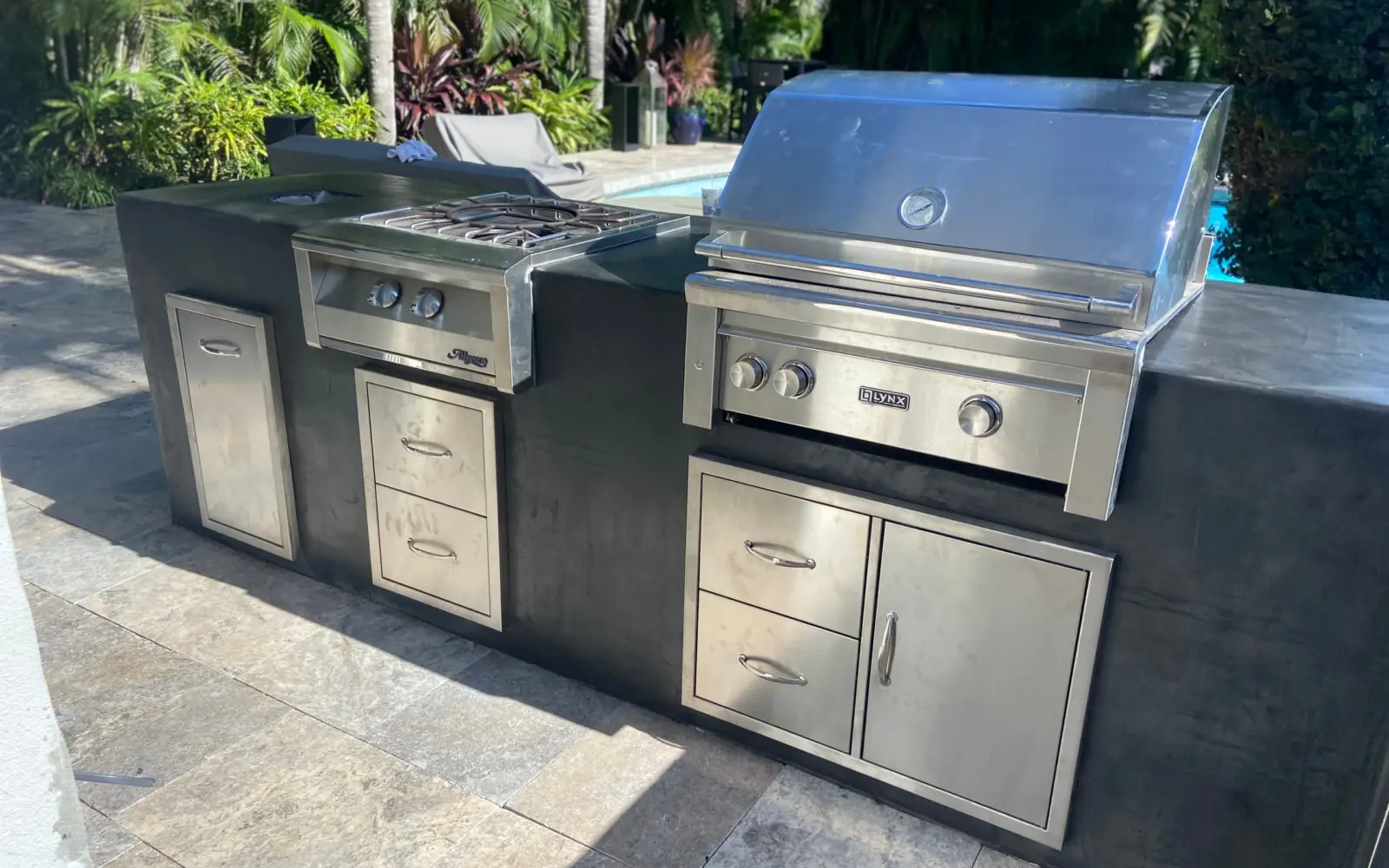 Outdoor kitchen island with smooth charcoal finish, Lynx grill, side burner and stainless drawers