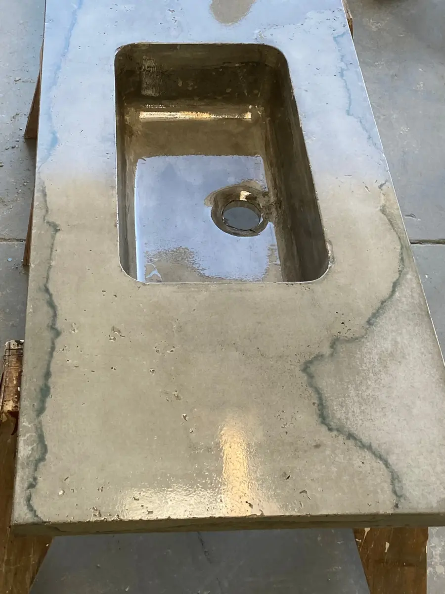 Gray concrete countertop with integral sink and blue-gray veining on sawhorses in a shop