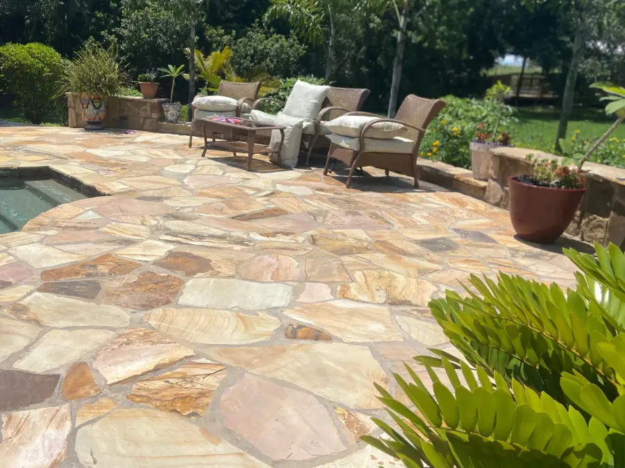 Flagstone patio of warm sandstone in irregular pieces with wicker seating beside a spa