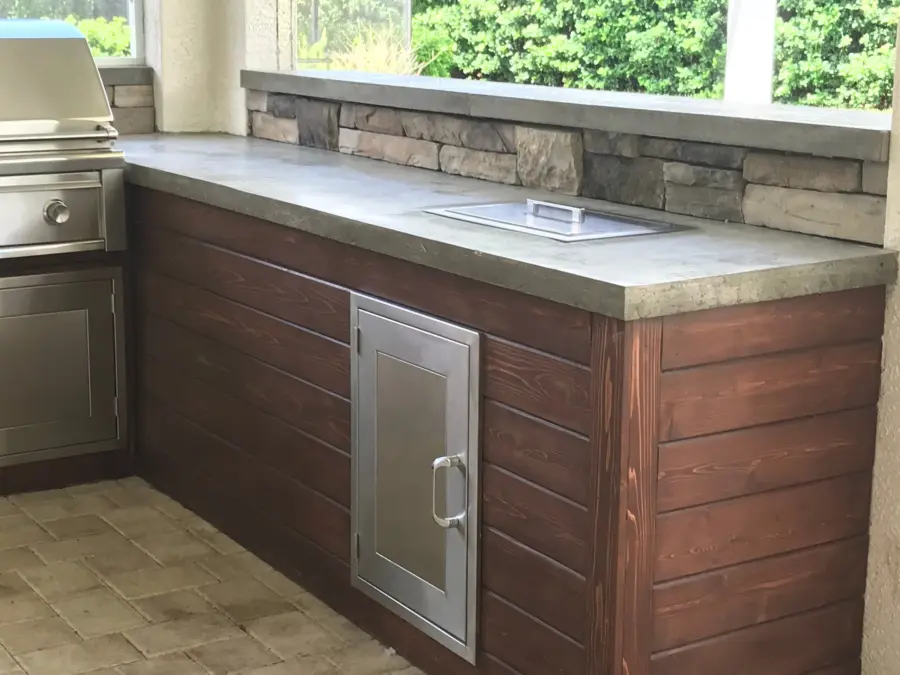 Gray concrete countertop with rough edge on a dark stained wood cabinet with stacked stone back