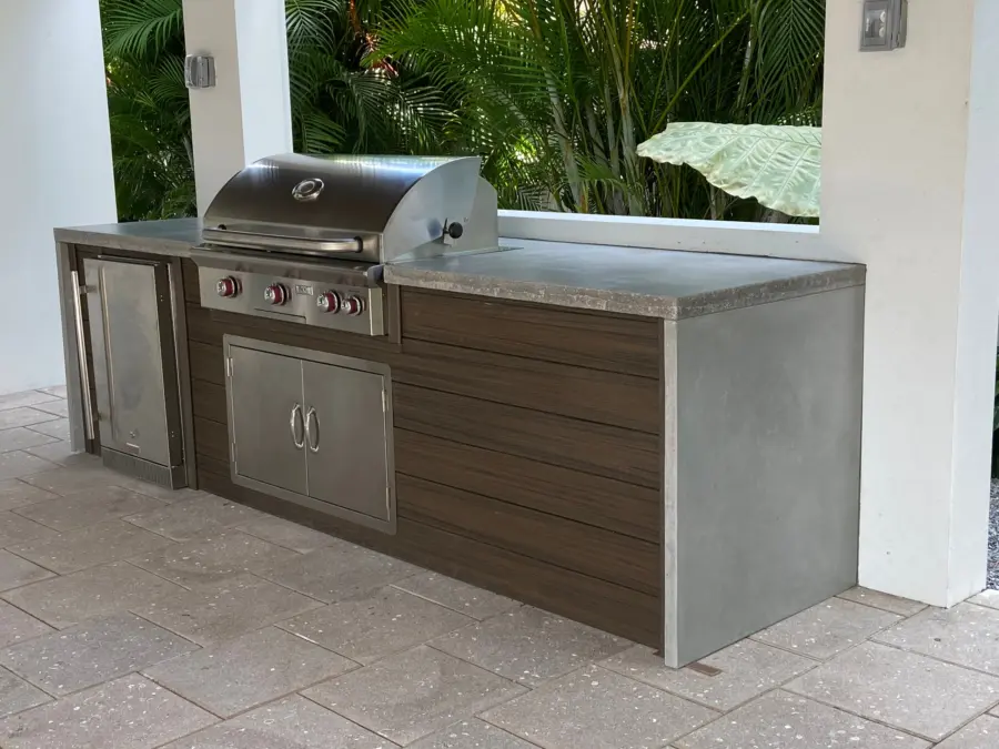 Gray concrete countertop with waterfall end on an outdoor kitchen with grill and wood-look panels