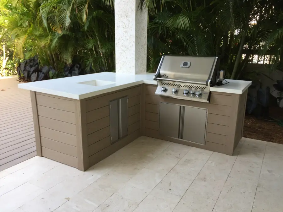 L-shaped outdoor kitchen with taupe wood-look panels, white countertop and Napoleon grill