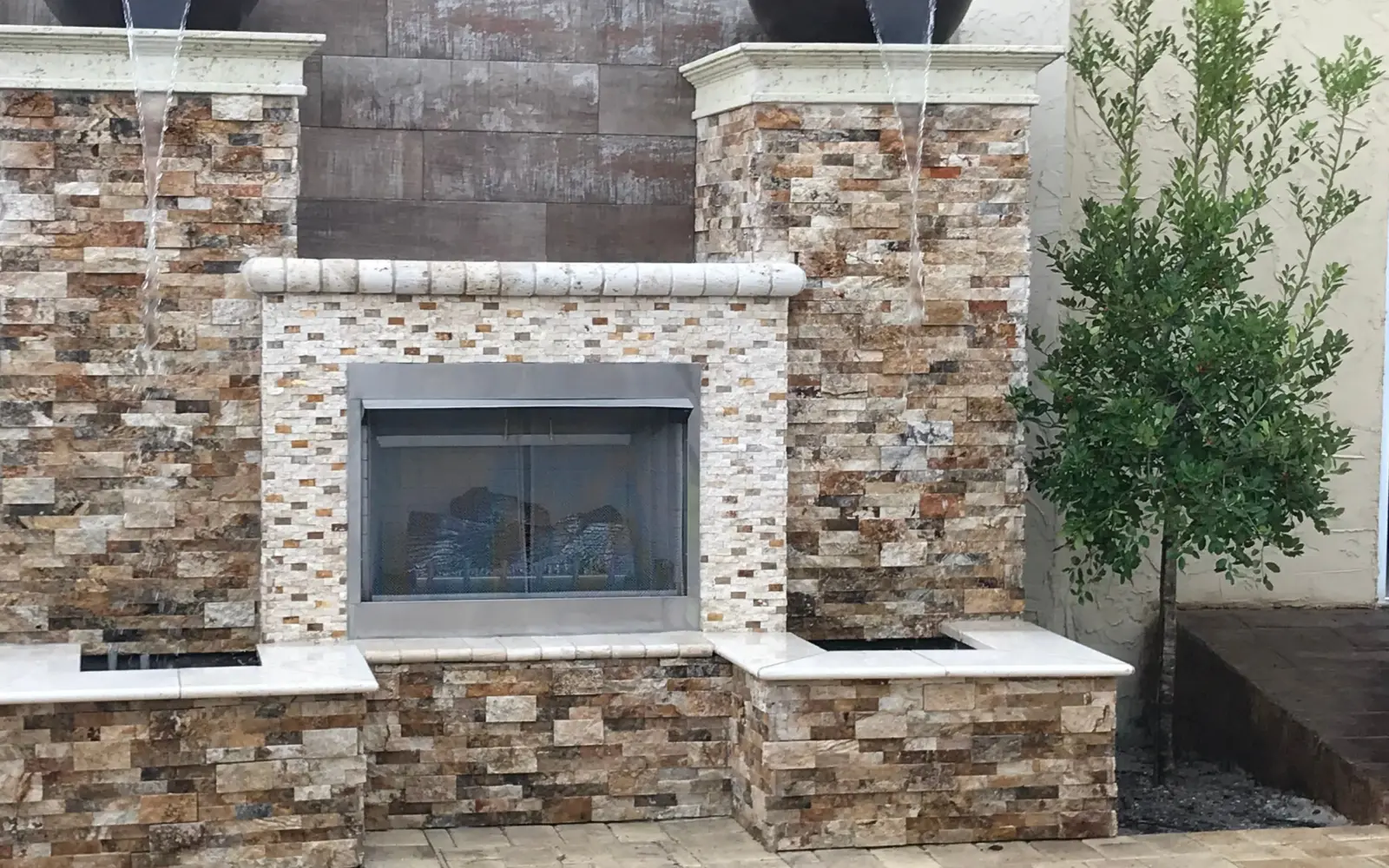 Stacked stone fireplace wall with gas fireplace and two bowls spilling water into stone basins