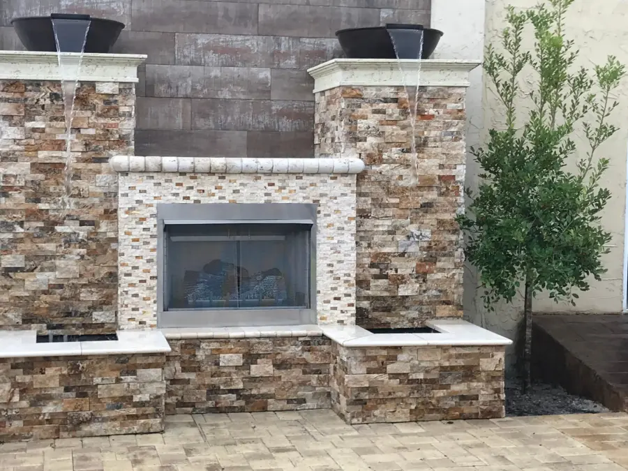 Stacked stone fireplace wall with gas fireplace and two bowls spilling water into stone basins