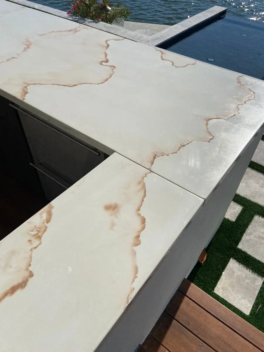 White concrete countertop with rust-colored veining and square edge on a waterfront outdoor bar