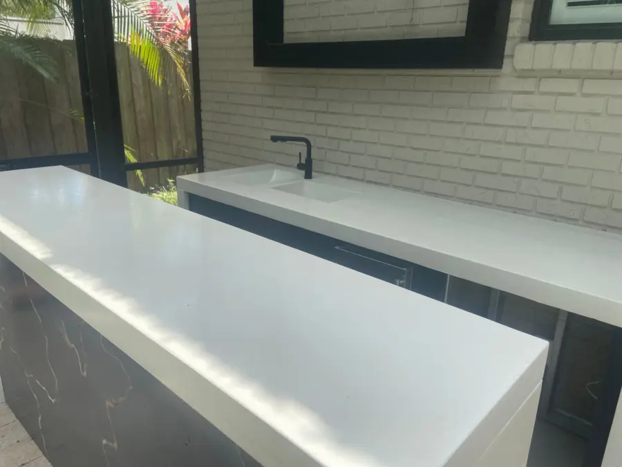 White concrete countertops with integral sink and black faucet against white painted brick