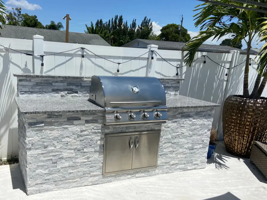 Grill island in white stacked stone with speckled stone countertop, Blaze grill and stainless doors